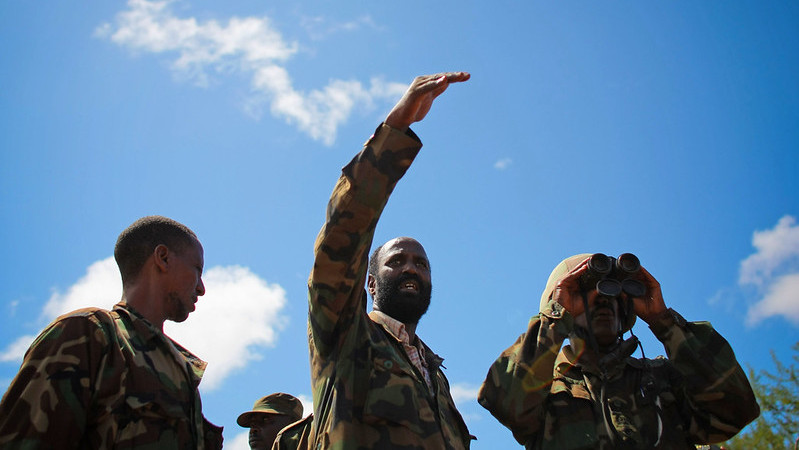 Three rangers seen from below, one looking through binoculars