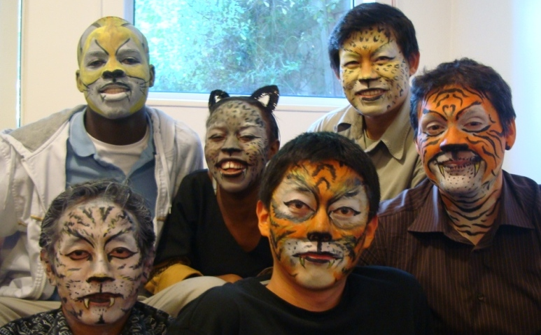 Six people with faces painted as different felid species